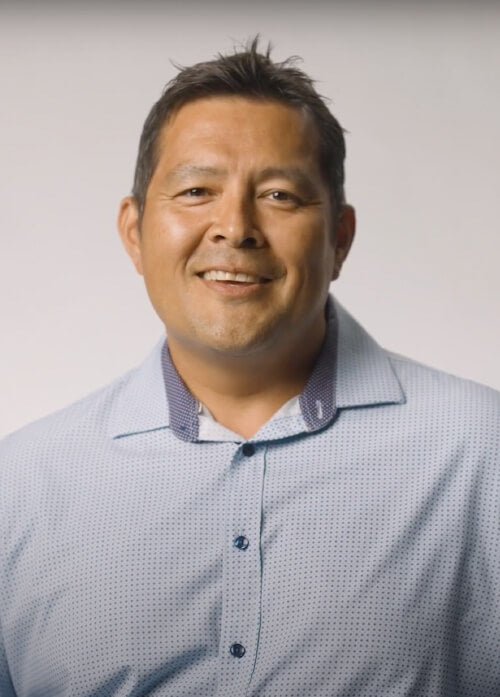A headshot of a man in a light blue shirt