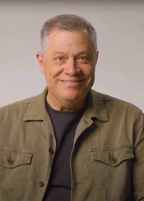 A headshot of a man in a green jacket